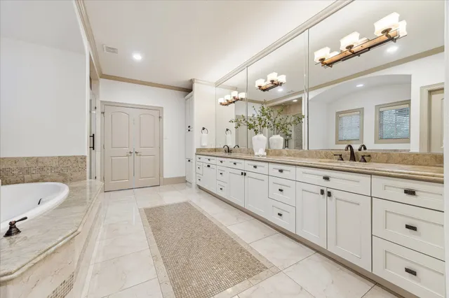 a spacious bathroom with a granite countertop double vanity sink a mirror a bathtub and