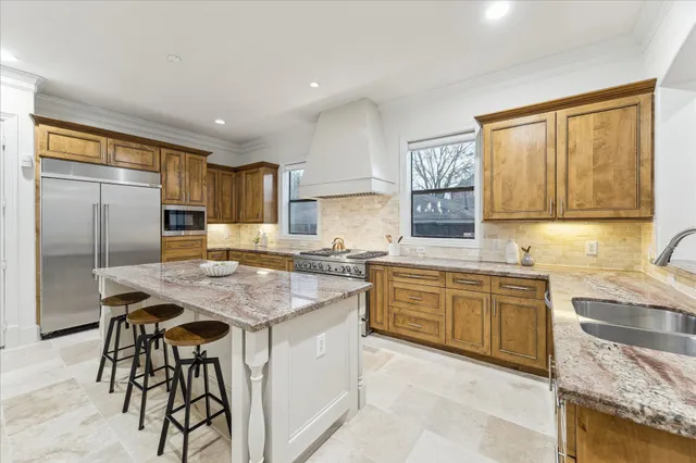 a kitchen with granite countertop stainless steel appliances a sink stove refrigerator and cabinets