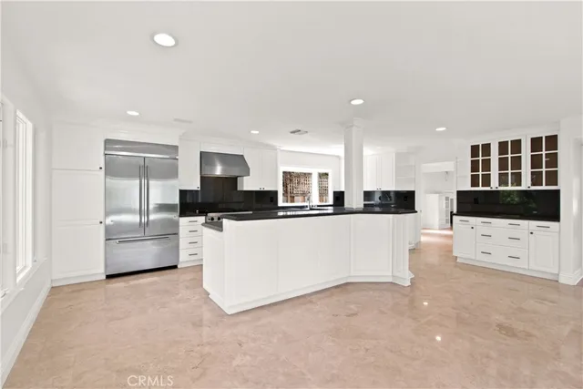 a large white kitchen with kitchen island a refrigerator a stove a sink dishwasher with a dining table and chairs