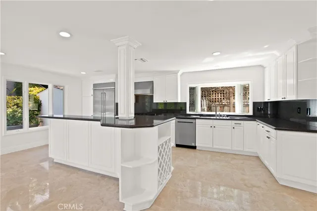 a large white kitchen with kitchen island a large counter top space a sink and appliances