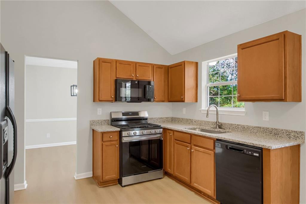 6566 Shaffers Way Lithonia, GA 30058 - Photo 8 of 31 a kitchen with stainless steel appliances granite countertop a sink stove and microwave