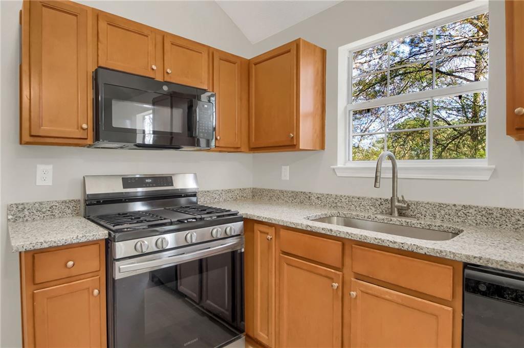 6566 Shaffers Way Lithonia, GA 30058 - Photo 9 of 31 a kitchen with stainless steel appliances granite countertop a sink stove and microwave