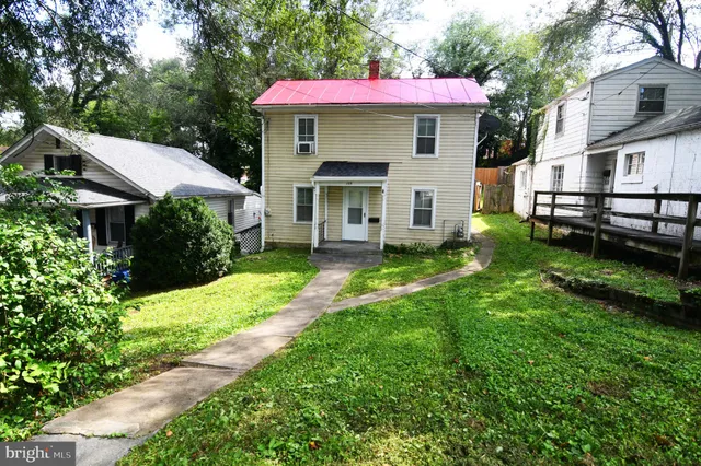 a view of a white house with a big yard plants and large trees
