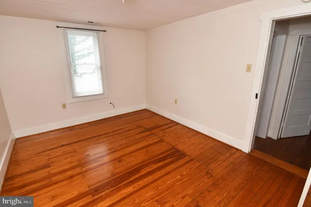 an empty room with wooden floor and a window