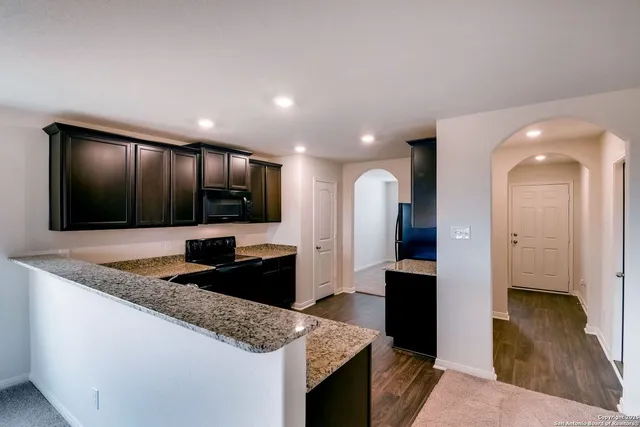 a kitchen with stainless steel appliances kitchen island granite countertop a refrigerator and a sink