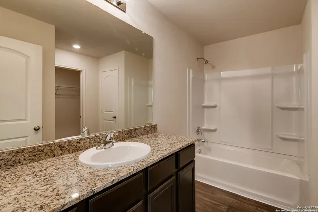 a bathroom with a granite countertop sink mirror and a bath tub