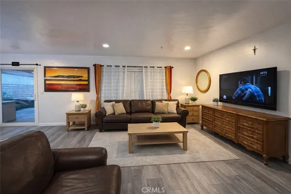 a living room with furniture a flat screen tv and kitchen view