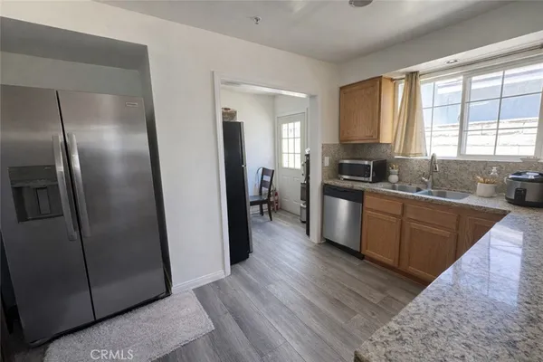 a kitchen with stainless steel appliances granite countertop a refrigerator a sink dishwasher a stove with wooden cabinets and a large window