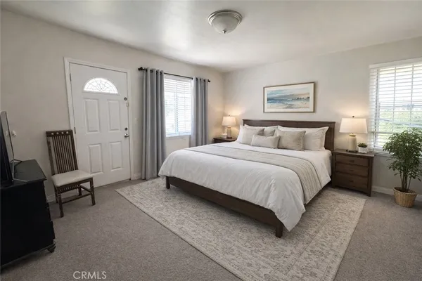a bedroom with a bed a chair and painting on the wall