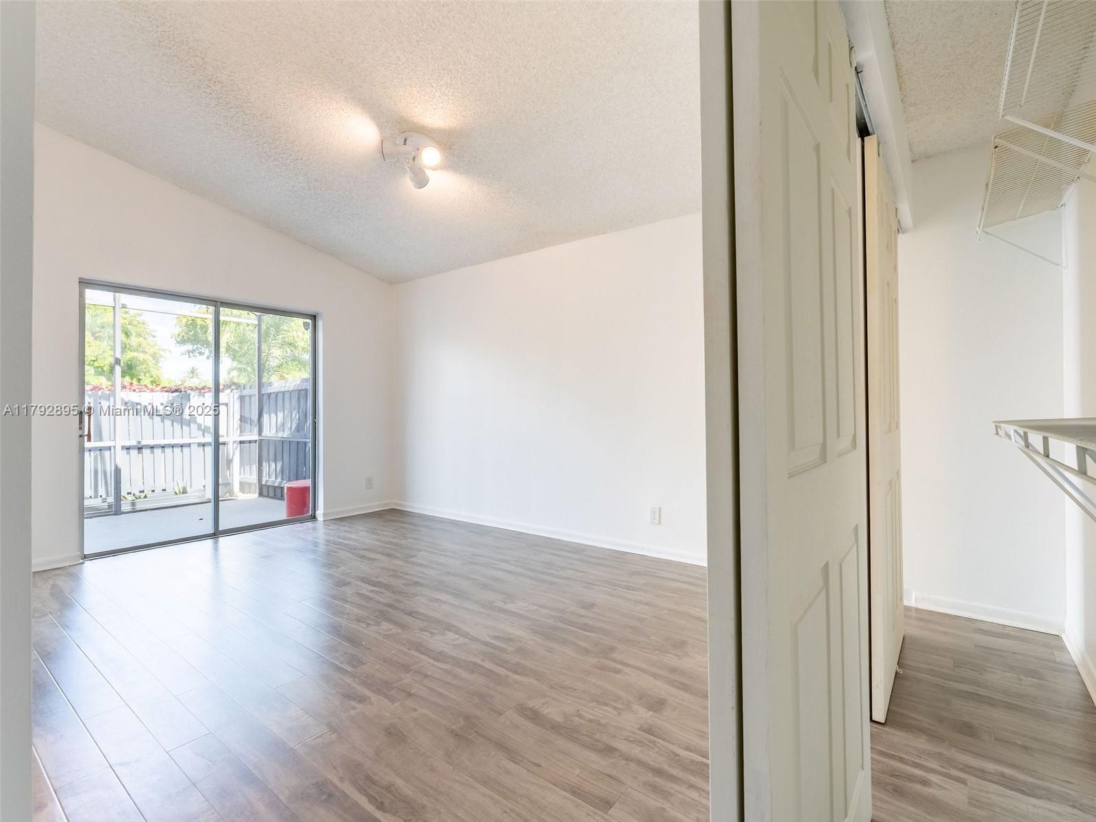 1225 Seagrape Circle Weston, FL 33326 - Photo 20 of 61 a view of an empty room with wooden floor and a window