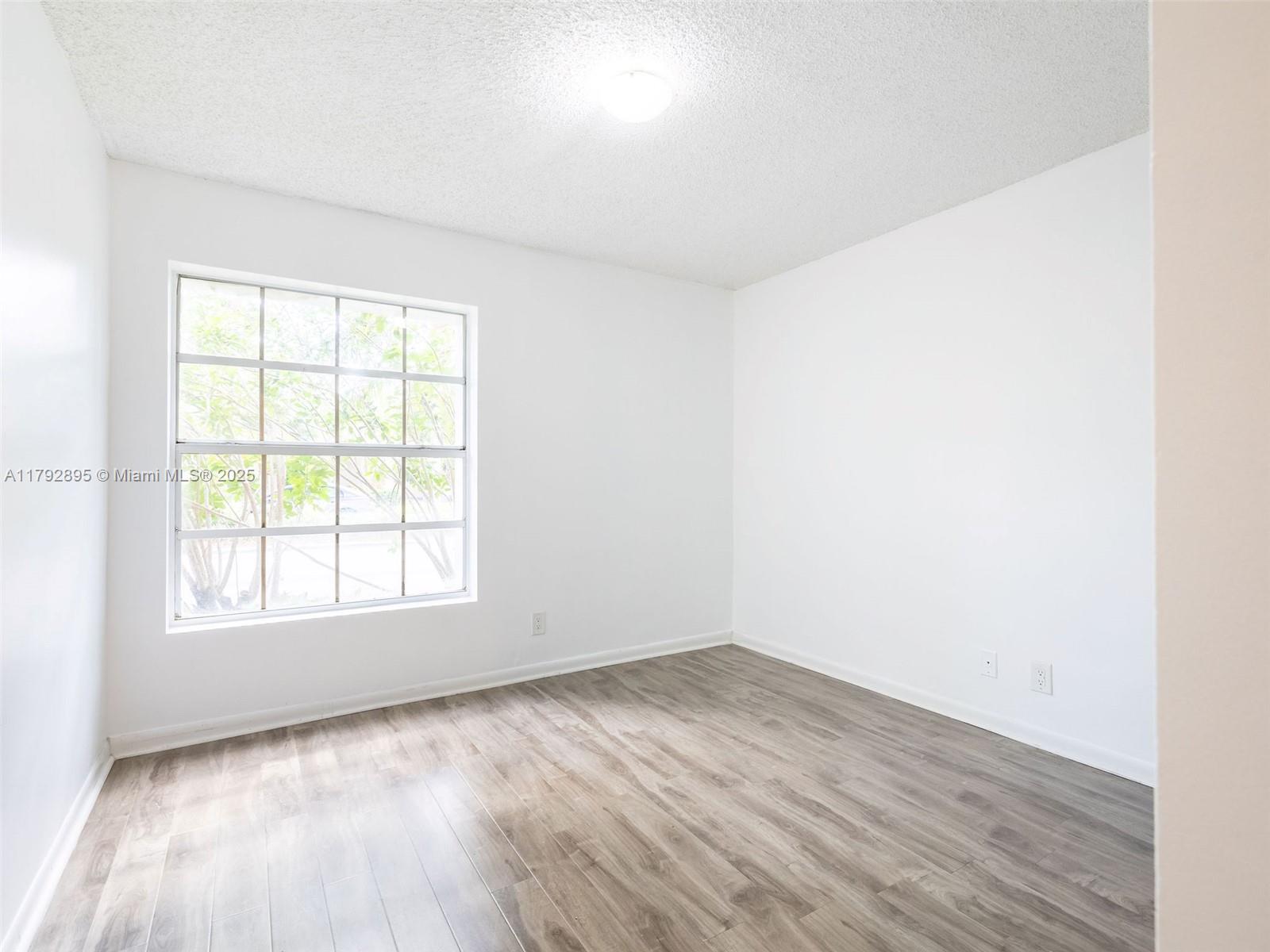1225 Seagrape Circle Weston, FL 33326 - Photo 31 of 61 an empty room with wooden floor and windows