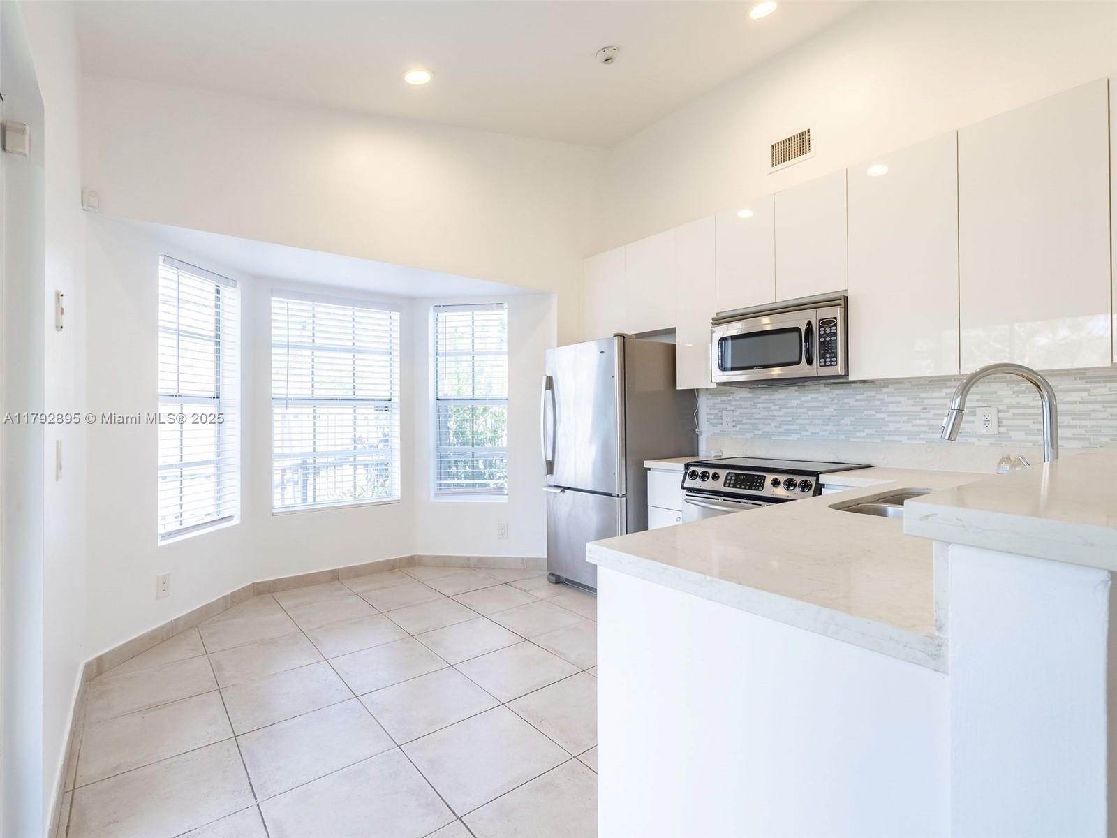 1225 Seagrape Circle Weston, FL 33326 - Photo 8 of 61 a kitchen with stainless steel appliances a sink stove refrigerator and a window