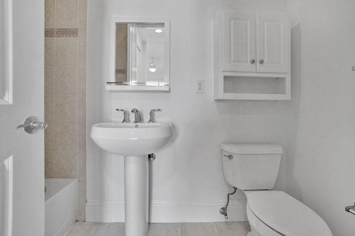 3120 East Latitude Circle, Unit 309 Delray Beach, FL 33483 - Photo 23 of 32 a bathroom with a toilet sink and mirror