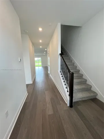 a view of a hallway with wooden floor and staircase