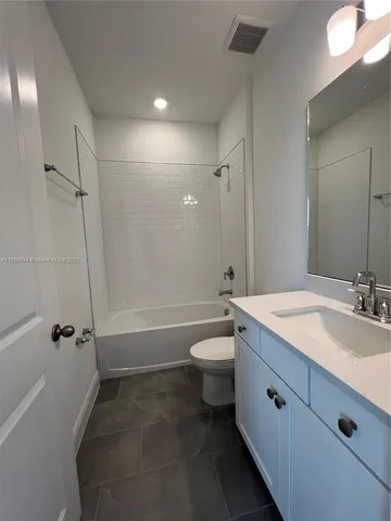 a bathroom with a granite countertop sink a toilet and shower