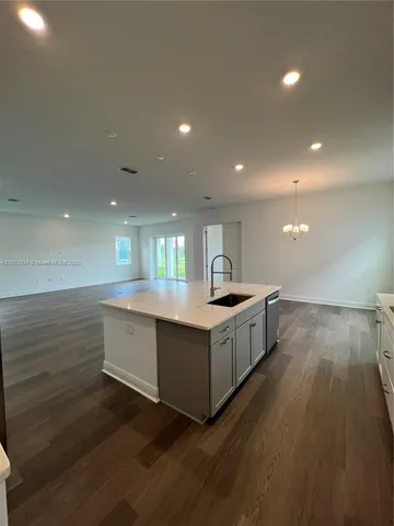 a large white kitchen with wooden floors and stainless steel appliances