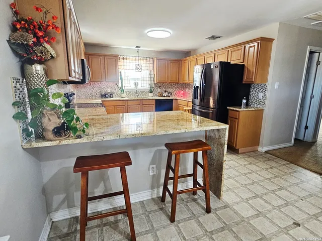 a kitchen with stainless steel appliances a dining table chairs refrigerator and sink