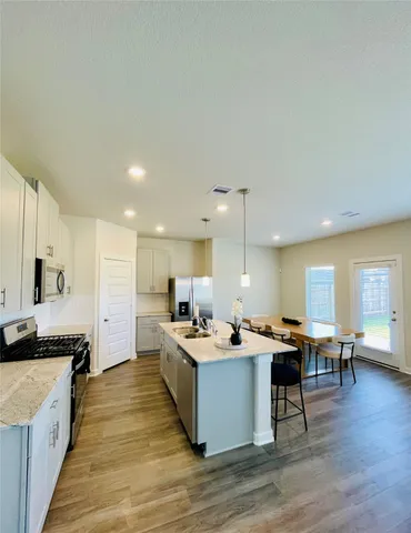 a large kitchen with a counter top space a sink stainless steel appliances and cabinets