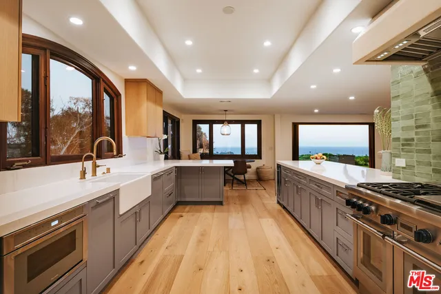 a large kitchen with stainless steel appliances granite countertop a lot of counter space and a sink