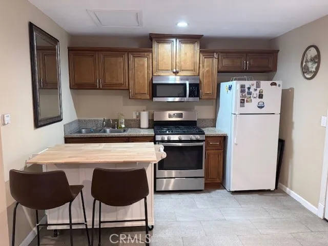 a kitchen with stainless steel appliances a stove a refrigerator a sink and a cabinets