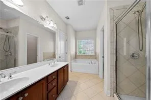 a spacious bathroom with a double vanity sink a large mirror and shower