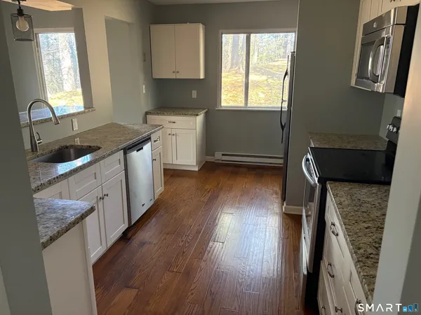 a kitchen with granite countertop a sink stove and cabinets