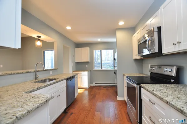 a large kitchen with stainless steel appliances granite countertop a lot of counter space and wooden floor