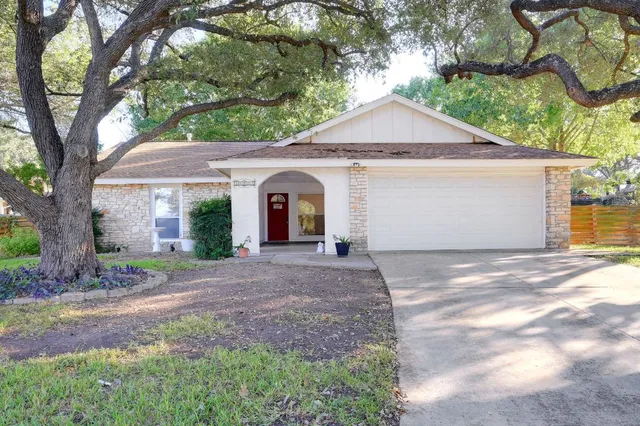 a view of a house with a yard and large tree