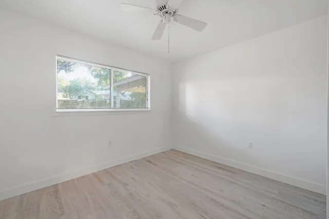 an empty room with a window and a ceiling fan