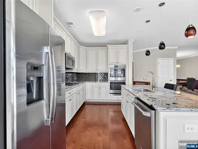 a large kitchen with stainless steel appliances granite countertop a lot of counter space and wooden floors