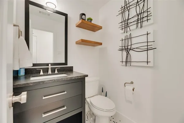 a bathroom with a granite countertop sink vanity mirror and toilet