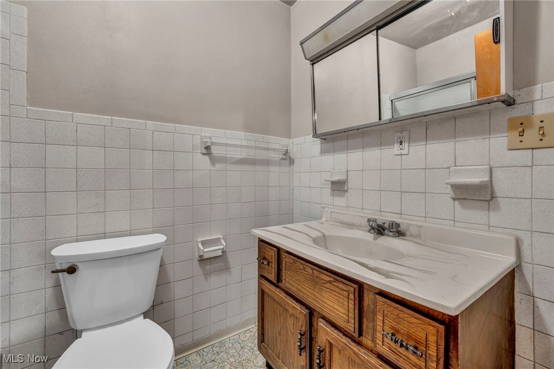 1140 Keefer Road Girard, OH 44420 - Photo 17 of 49 Bathroom featuring vanity, tile walls, and wainscoting