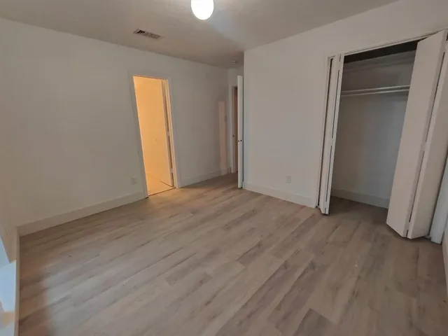 an empty room with wooden floor and closet