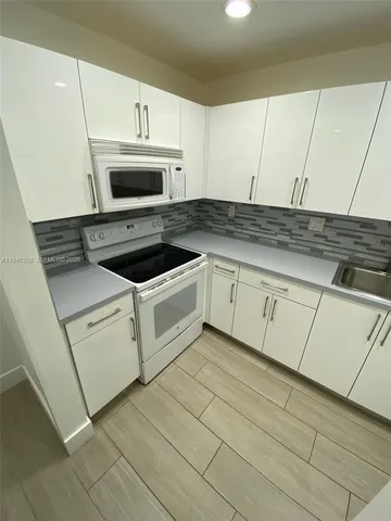 a kitchen with granite countertop white cabinets and white appliances