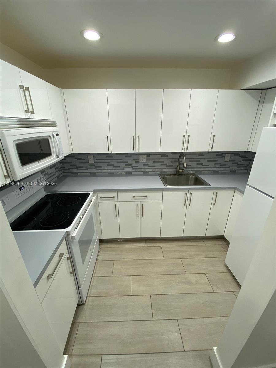 4805 Northwest 7th Street, Unit 10315 Miami, FL 33126 - Photo 5 of 22 a kitchen with granite countertop white cabinets and white appliances