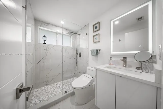 a bathroom with a granite countertop sink toilet a mirror and shower