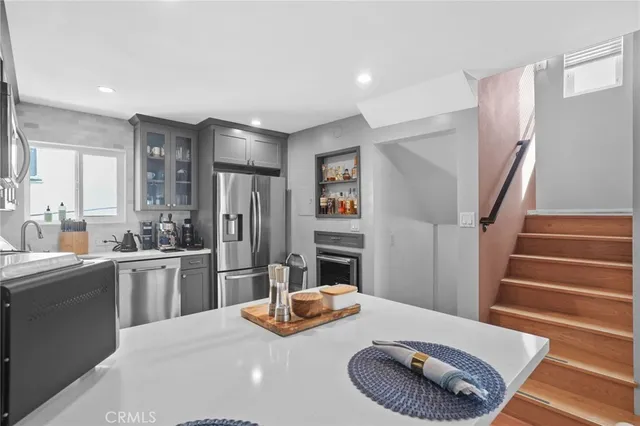 a kitchen with stainless steel appliances kitchen island granite countertop a refrigerator a stove a sink and a dining table with wooden floor