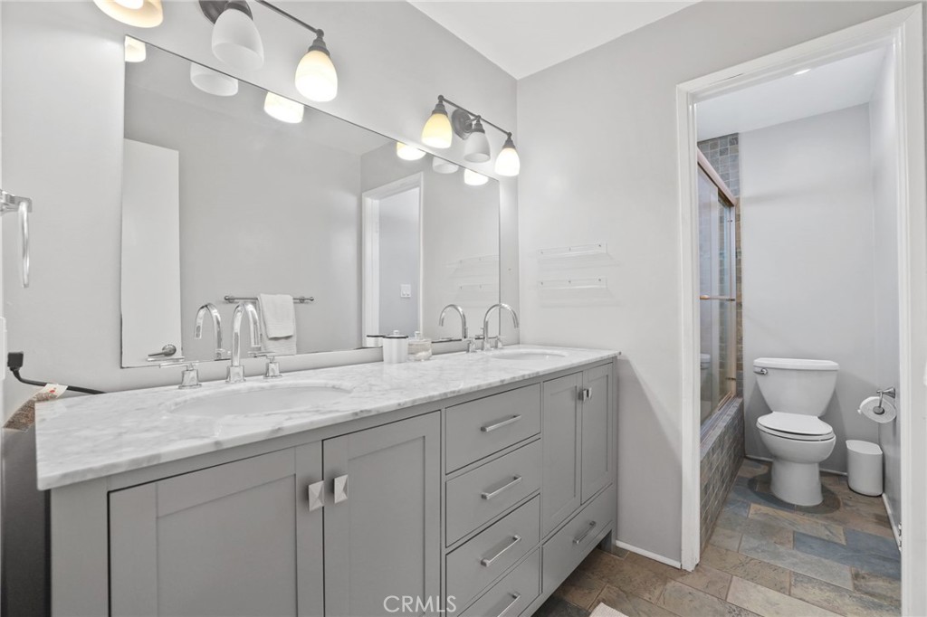 11954 Goshen Avenue, Unit 205 Los Angeles, CA 90049 - Photo 38 of 48 a bathroom with a granite countertop sink a toilet and a mirror