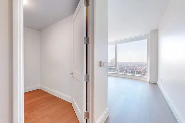 a view of a hallway with wooden floor and a bathroom