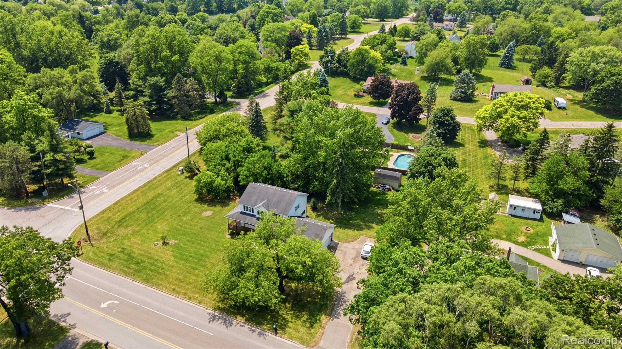 4482 Pleasant Valley Road Brighton, MI 48114 - Photo 28 of 35 Aerial perspective showcasing a residential property with a light-colored exterior and dark roof, surrounded by mature trees