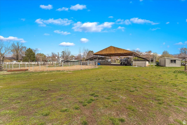 5321 South 3100th Street West Roy, UT 84067 - Photo 20 of 64 Expansive green space featuring a covered outdoor structure, a fenced arena, a detached shed, and a mountain backdrop
