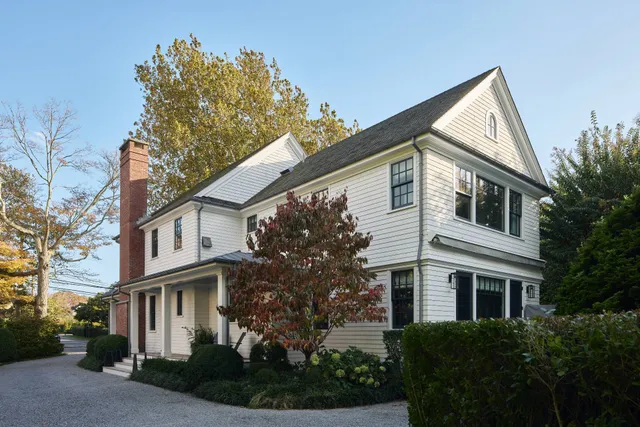 a view of a white house next to a yard
