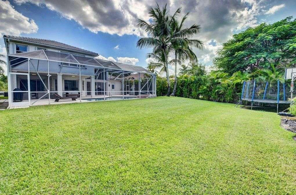 11119 Blue Coral Drive Boca Raton, FL 33498 - Photo 3 of 36 front view of a building with a yard and palm trees