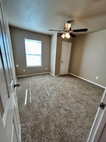 en empty room with windows and ceiling fan