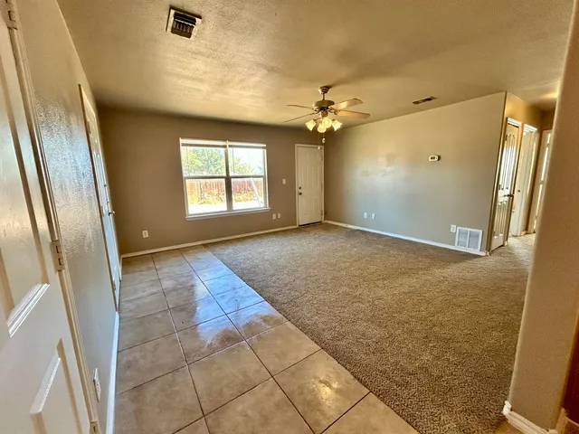 an empty room with windows and fan