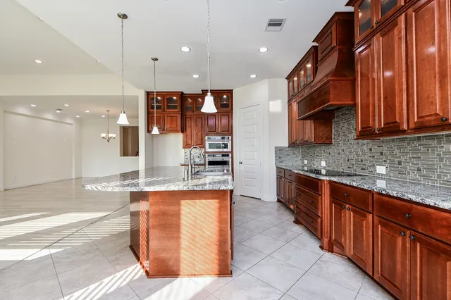 a kitchen with kitchen island granite countertop a stove and a sink