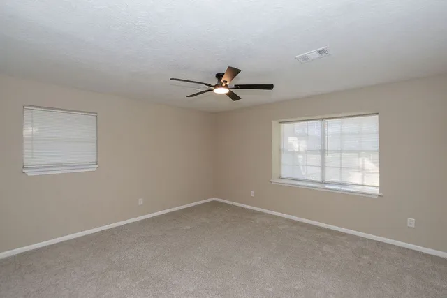 an empty room with a window and a ceiling fan
