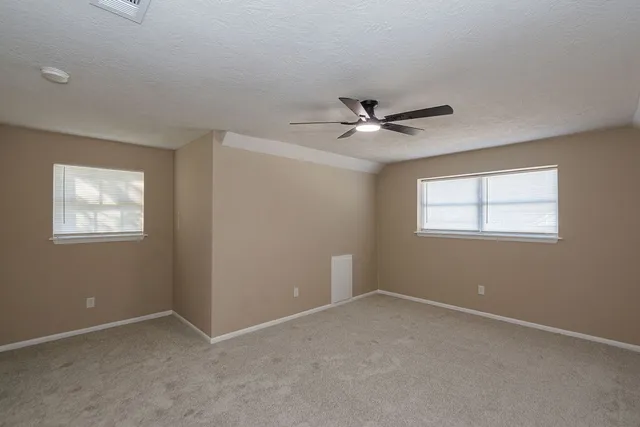 an empty room with a window and a fan