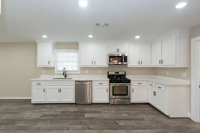 a kitchen with white cabinets stainless steel appliances and sink