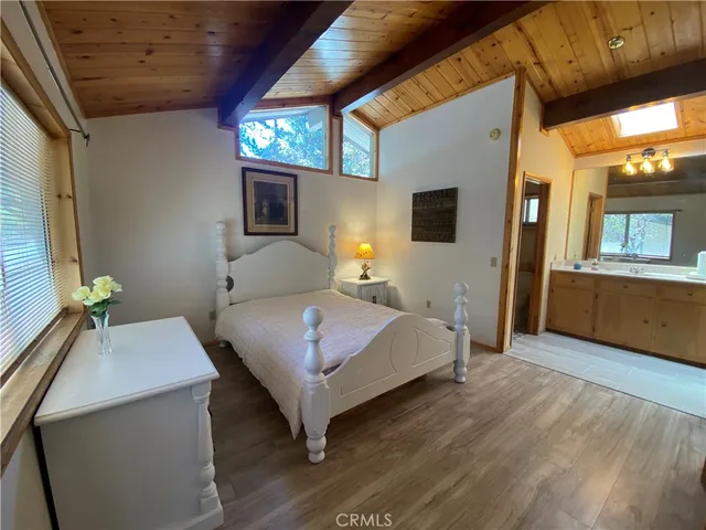a spacious bedroom with a bed and a dresser with wooden floor